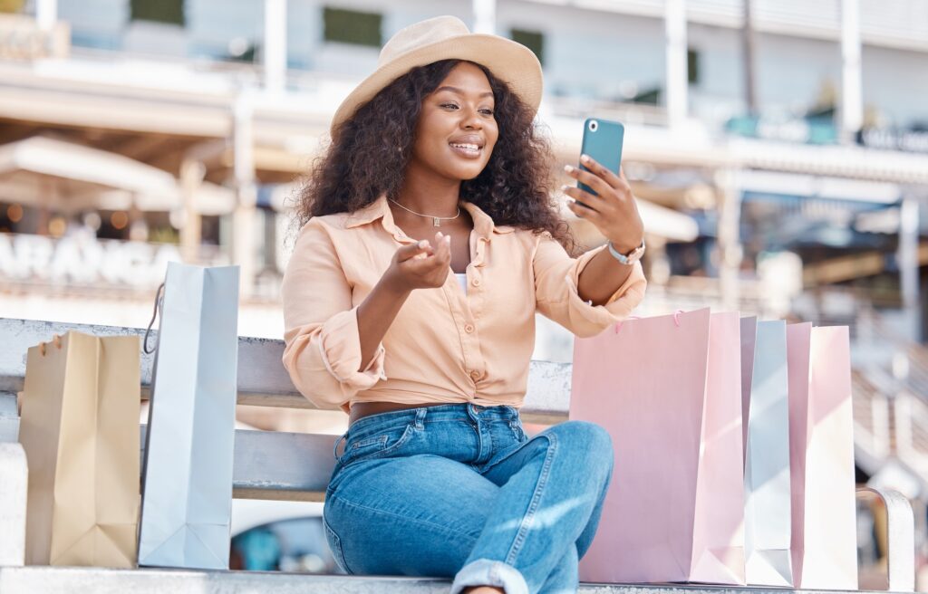 Retail, shopping and video call with black woman and phone in city for social media influencer, lux